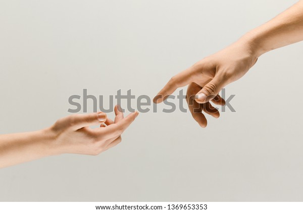 Moment of weightless. Two male hands trying to\
touch like a creation of Adam sign isolated on grey studio\
background. Concept of human relation, community, togetherness,\
symbolism, culture and\
history