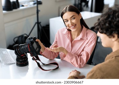 Moments captured. Young photographer woman showing photos work to male model in studio, talking after photoshoot and choosing the best pictures, sitting at workplace - Powered by Shutterstock