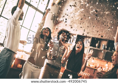 Moments of happiness. Cheerful young people throwing confetti and smiling while enjoying home party on the kitchen 