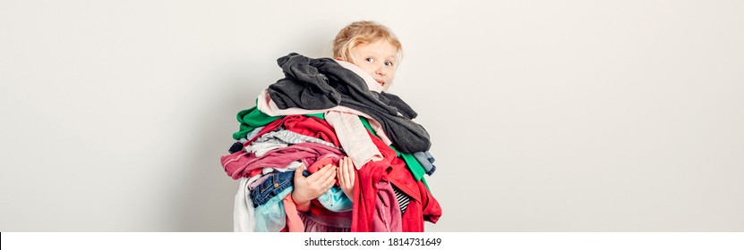 Mommy Little Helper. Adorable Funny Child Arranging Organising Clothing. Kid Holding Messy Stack Pile Of Clothes Things. Home Chores Housework. Web Banner Header.