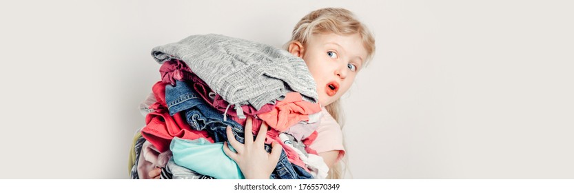 Mommy Little Helper. Funny Cute Girl Child Arranging Organazing Clothing. Kid Holding Messy Stack Pile Of Clothes Things. Home Chores Housework. Web Banner Header For Website.