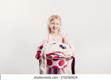 Mommy Little Helper. Smiling Caucasian Girl Child Holding Wash-basin With Clothes And Laundry Detergent Pods. Kid With Messy Stack Of Clothes. Home Chores Housework For Children.