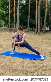 Mommy And Me Yoga For Babies And Postpartum Moms. Zen Family Yoga. Postpartum Mother And Baby Girl Daughter Having Outdoor Yoga Classes In Nature Background