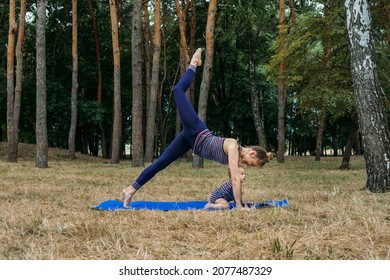 Mommy And Me Yoga For Babies And Postpartum Moms. Zen Family Yoga. Postpartum Mother And Baby Girl Daughter Having Outdoor Yoga Classes In Nature Background