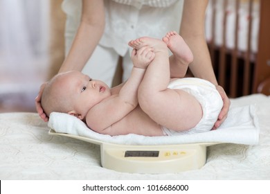 Mommy Is Measuring Baby Weigh On Scales At Home