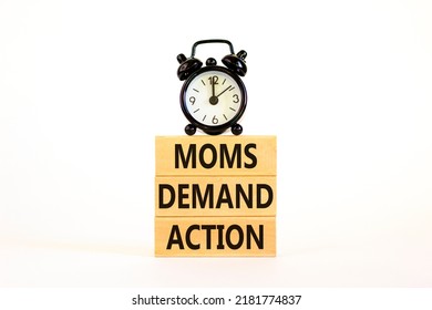Moms demand action symbol. Concept words Moms demand action on wooden blocks on a beautiful white table white background. Black alarm clock. Business, finacial and Moms demand action concept.