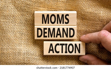Moms demand action symbol. Concept words Moms demand action on wooden blocks on a beautiful canvas table canvas background. Businessman hand. Business, finacial and Moms demand action concept.