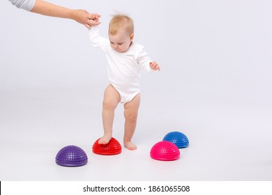 Mom's Hand Holding Baby Girl In White Bodysuit With Physiotherapy Tools For Flat Feet-balance Pod On White Background