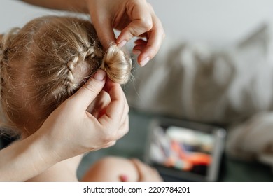 Mom's Hands Weave A Braid On The Head Of A Blonde Daughter. Close-up. Mother And Child Spend Time Together.