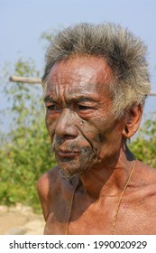 Mon district, Nagaland, India - 02 27 2013 : Closeup three quarter outdoor portrait of old Naga Konyak tribe head hunter warrior with traditional facial tattoo on natural background
