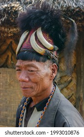 Mon district, Nagaland, India - 02 28 2013 : Three quarter portrait of aging Naga Konyak tribe man with typical hair style wearing traditional red cane hat with boar tusks, fur and horse hair