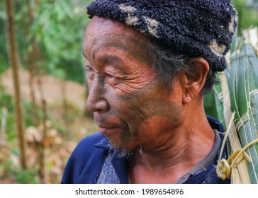 Mon district, Nagaland, India - 03 02 2009 : Closeup three quarter outdoor portrait of senior Naga Konyak tribe head hunter warrior with traditional facial tattoo on nature background