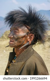 Mon district, Nagaland, India - 03 10 2014 : Closeup outdoor profile portrait of old Naga Konyak tribe head hunter warrior with traditional facial tattoo, fur hat and spectacular horn earrings
