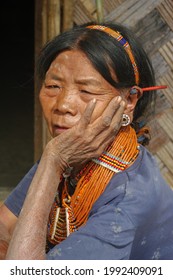 Mon district, Nagaland, India - 03 11 2014 : Outdoor three quarter portrait of old Naga Konyak tribal woman wearing traditional necklace, headband and porcupine quills in her ears indicating status
