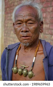 Mon district, Nagaland, India - 11 19 2010 : Closeup outdoor portrait of senior Naga tribe warrior with faint traditional facial tattoo wearing typical head hunter necklace