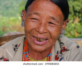 Mon district, Nagaland, India - 11 18 2010 : Closeup portrait of smiling old Naga Konyak tribe woman wearing traditional necklace and earrings on natural background
