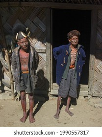 Mon district, Nagaland, India - 11 25 2013 : Full length portrait of two old traditional Naga Konyak tribal warriors wearing typical hats outside their house