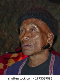 Mon district, Nagaland, India - 11 25 2013 : Close up indoor portrait of middle aged Naga Konyak tribe man wearing spectacular wild goat (serow) horn earrings and fur hat on dark background