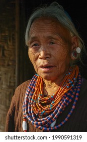 Mon, Nagaland, India - 02 28 2013 : 
Portrait of beautiful old Naga Konyak tribe woman standing at her doorstep wearing traditional necklace and earrings