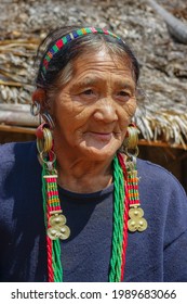 Mon, Nagaland, India - 03 03 2009 : Portrait of old Naga Konyak tribal woman standing outside her village house with spectacular earrings and colorful traditional jewellery