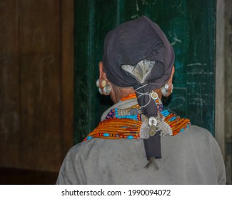 Mon, Nagaland, India - 03 03 2009 : Back portrait of old Naga Konyak tribe woman showing beautiful traditional necklace and earrings with black head scarf
