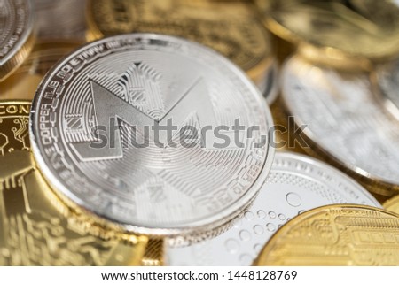 Monero physical coin on the stack of other different cryptocurrencies. Close-up photo of monero with shallow depth of field