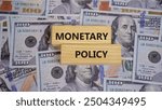 MONETARY POLICY symbol. Copy space. Concept word MONETARY POLICY on wooden blocks with dollar notes on the background. Business and financial concept.