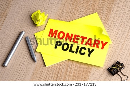 MONETARY POLICY text on a yellow sticky on wooden background