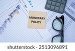 MONETARY POLICY word. Copy space. Concept word MONETARY POLICY on wooden blocks with diagram chart and office stuffs on the background. Business and financial concept.