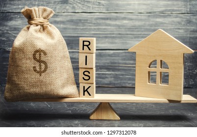 Money Bag, Blocks With The Word Risk And A Wooden House On The Scales. The Concept Of Losing Money When Investing In Real Estate. Risks Of Losing A Home Or Housing For Non-payment. Property Insurance