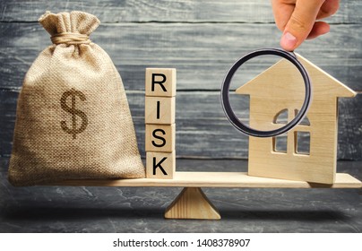 Money Bag, Blocks With The Word Risk And A Wooden House On The Scales. The Concept Of Losing Money When Investing In Real Estate. Risks Of Losing A Home Or Housing For Non-payment. Property Insurance