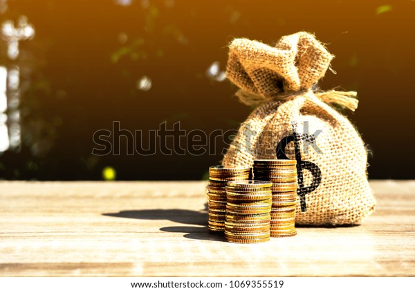 Money bag and coins on orange light background\
present the savings planting. or savings to buy a home or real\
estate. Or show divide the investment. Loan Or for the future\
Concept of money