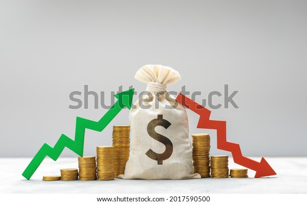 Money bag with daollar sign.\
Graph is growing green arrow up and graph of falling red arrow down\
on the background of a stack of coins. Market fluctuation\
concept.