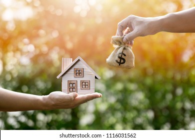 Money bag home and man hands in sunlight represent to exchange or saving money or investing to buy a home or loan to buy a house or real estate or investment for the future. - Shutterstock ID 1116031562