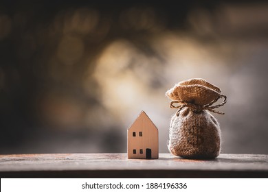 Money bag and home model put on the wood with growing interest in the public park, Saving money for buy house or loan for investment of real estate concept.