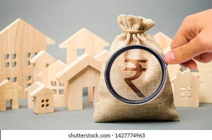 Money bag with a sign indian rupee (rupiah) and wooden houses. The concept of real estate market. Pricing and demand. City budget. Rental and sale of housing. Mortgage and loan. Purchase of apartments