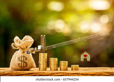 Money bag and stacking gold coins with increase and tower crane and hoist brake solutions with build new house in the public park, saving money and loan for construction real estate and home concept.