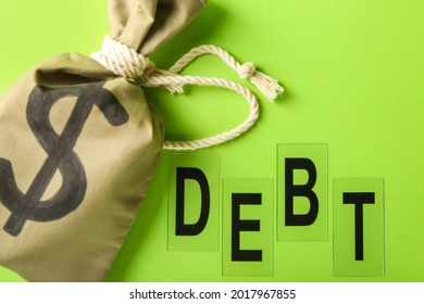 Money Bag And Word DEBT On Color Background