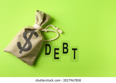 Money Bag And Word DEBT On Color Background