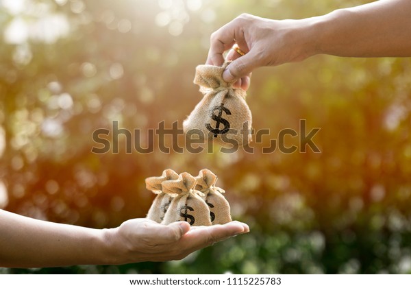 Money bags and man hand and giving in sunlight\
show giving savings or Loan to Buy Assets or give money to pay in\
the future or divide the investment for retirement or for the\
future Concept of money.