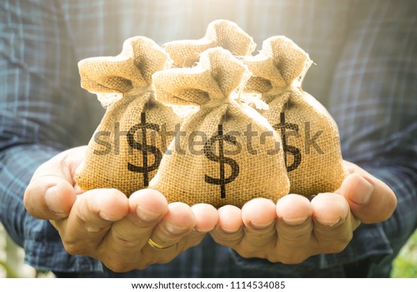 Money bags in man hand show savings money and\
savings to buy a home or buy real estate or car. Or show a home\
loan or divide the investment for retirement. Or for the future\
Concept of money.