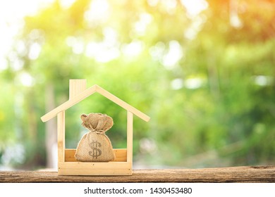 Money bags in the wooden home model  put on the old wood in the public park, Saving money for buy a new house or loan for plan business investment of real estate concept.