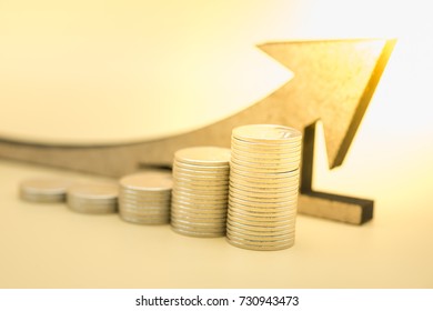 Money, business, saving and growth concept. Close up of stack of silver coins with wooden arrow symbol.