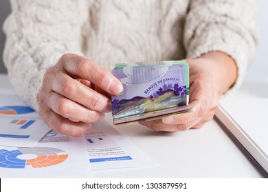 Money From Canada: Canadian Dollars. Old Woman Counting Bills On Table.