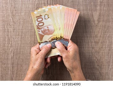 Money from Canada: Canadian Dollars. Overhead of senior person holding bills.
