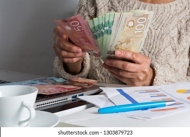 Money From Canada: Canadian Dollars. Senior Person Handling Bill On Desk.