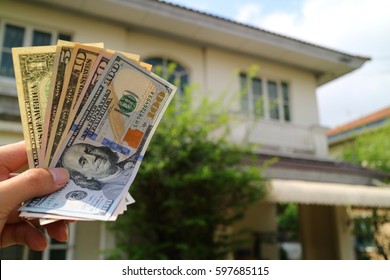 Money Cash On Hand With House Property Background. Property Investment, House Purchasing Concept