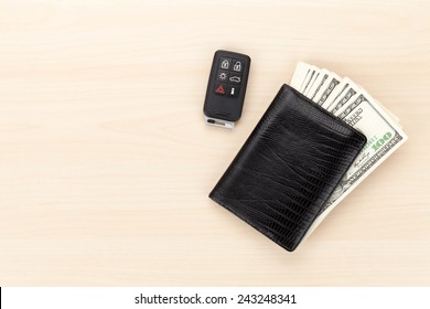 Money cash wallet and car remote key on wooden table. View from above with copy space