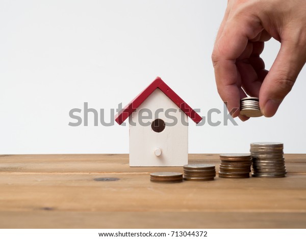 Money coins stack growing with red house on wood\
background. Business growth investment and financial concept\
ideas.Real estate investment. House and coins on table.Save money\
with stack coin.