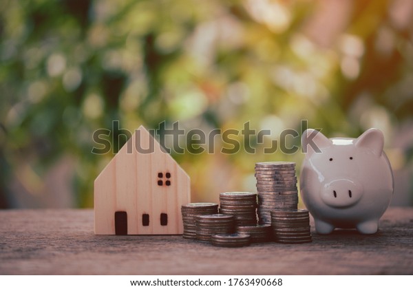 Money coins stack with\
piggy bank to show concept, saving money, land and house, loan,\
money investment, budget income, future, business financial on\
bokeh background.